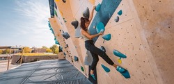 Bouldering climbing athlete woman training strength at outdoor gym boulder climb wall. Asian fit girl going up having fun in extreme sport hobby. Banner panoramic
