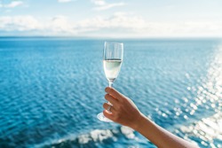 Champagne glass woman's hand toasting on ocean background at luxury cruise ship during sunset. Travel vacation for honeymoon, lady holding flute wearing wedding ring.