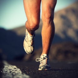 Running sport. Man runner legs and shoes in action on road outdoors at sunset. Male athlete model.