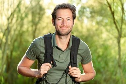 Young man hiking smiling happy portrait. Male hiker walking in forest.