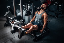 Muscular man using weights machine for legs at the gym. Hard training