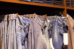 Fashion clothes on the shelves in the store. Jeans, shirts, pants hanging on hangers in the fashion store. Storefront, sale, shopping