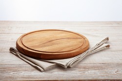 Empty pizza board and canvas tablecloth on white wooden deck. Selective focus.