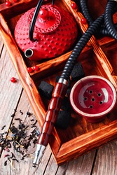 Hubble-bubble.Details of smoking hookah,cast iron red teapot in wooden box
