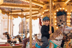Little boy enjoying his ride at carousel in amusement park