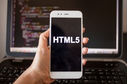 Mobile application development, HTML5 programming language for mobile development. Smartphone in hand with the inscription HTML5 on the screen