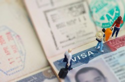 Miniature toys studio set up - expatriate business man and other travellers travel with visa on passport as background.