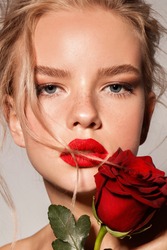 Young girl with red lips and rose. Blonde. Make up. Perfect style.