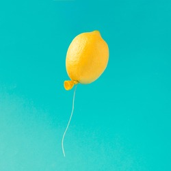Lemon balloon on bright blue background. Minimal summer fun concept.