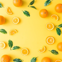 Creative summer pattern made of oranges and green leaves on pastel yellow background. Fruit minimal concept. Flat lay.