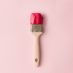 Creative spring concept made with paint brush and red tulip flower on pastel pink background. Minimal nature flat lay.