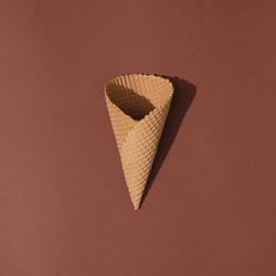 Ice cream cone on brown background. Minimal summer food concept. Flat lay.