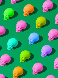 Pattern of colorful skulls on a vivid green background. Spooky concept. Halloween or Santa Muerte idea.