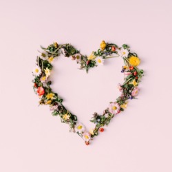 Heart symbol made of flovers and leaves on white background.