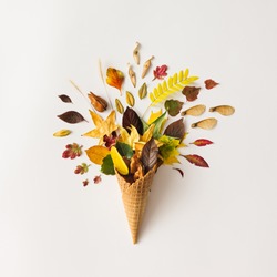 Colorful bright creative layout. Ice cream cone with autumn leaves. Flat lay.