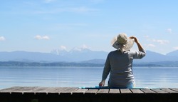 beautiful view at mountains,senior woman with hat on a wooden jetty at lake