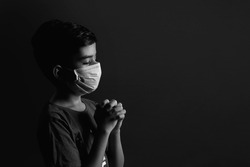 Portrait of Indian Little boy wearing mask and praying against the Coronavirus