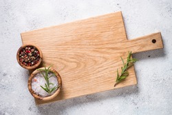Wooden cutting board with sea salt and pepper on white stone table. Top view copy space.