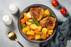 Baked chicken with vegetables. One pot dish. Baked in orange sauce. Top view on stone table.