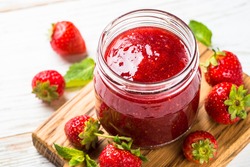 Strawberry jam in the glass jar with fresh berries. Close up.