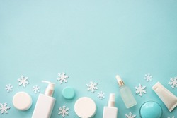 Winter cosmetic with holiday decorations. Make up products and christmas decor on blue. Christmas sale and gift concept. Flat lay with copy space.