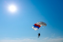 Parachutist is flying slowly down with an open parachute. Skydiving, gliding, parachute jump