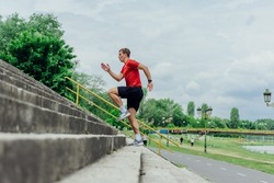 Fit male athlete performing stairs workout, running up climbing stairs performing outdoor track cardio.