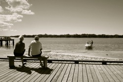 Older couple sit on a bench watching the fishing boats.