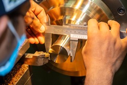 The machine operator measure the dimension of brass shaft by Vernier caliper. The quality control process of hi-precision parts manufacturing process.