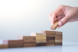 Hand arranging wood block stacking as step stair. Business concept for growth success process.