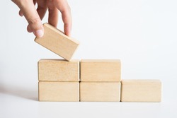 Hand aranging wood block stacking as step stair. Business concept for growth success process.