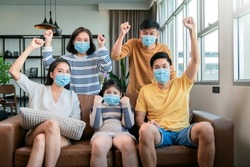 asian family strong together against covid virus epidemic spread,asian multi generation family with face mask cheering hand rise up show how strong healthy they have,family smile with confident home