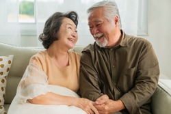 old senior asian retired age marry couple wellness lifesstyle together at home,old people laugh smile together with love and bonding on sofa in living room home interior background