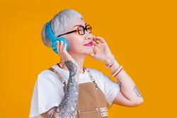 trendy asian senior old woman female wear headphone listening music melody while wear apron hand touch earphone casual relax lifestyle,easy listening music asia woman with tattoo close eye feel free