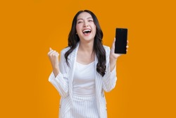 exited surprise face expression asian business woman female hand gesture exited with successful progress result on smartphone screen display  exited raised hands up isolated on bright yellow color