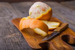 Peeled orange on wooden cutting board