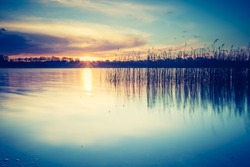 Vintage photo of beautiful sunset over calm lake. Mazury lake district landscape.