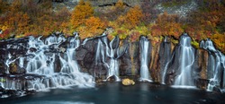 Stunning smooth waterfall background with yellow leaf at Hraunfossar, Iceland during autumn season