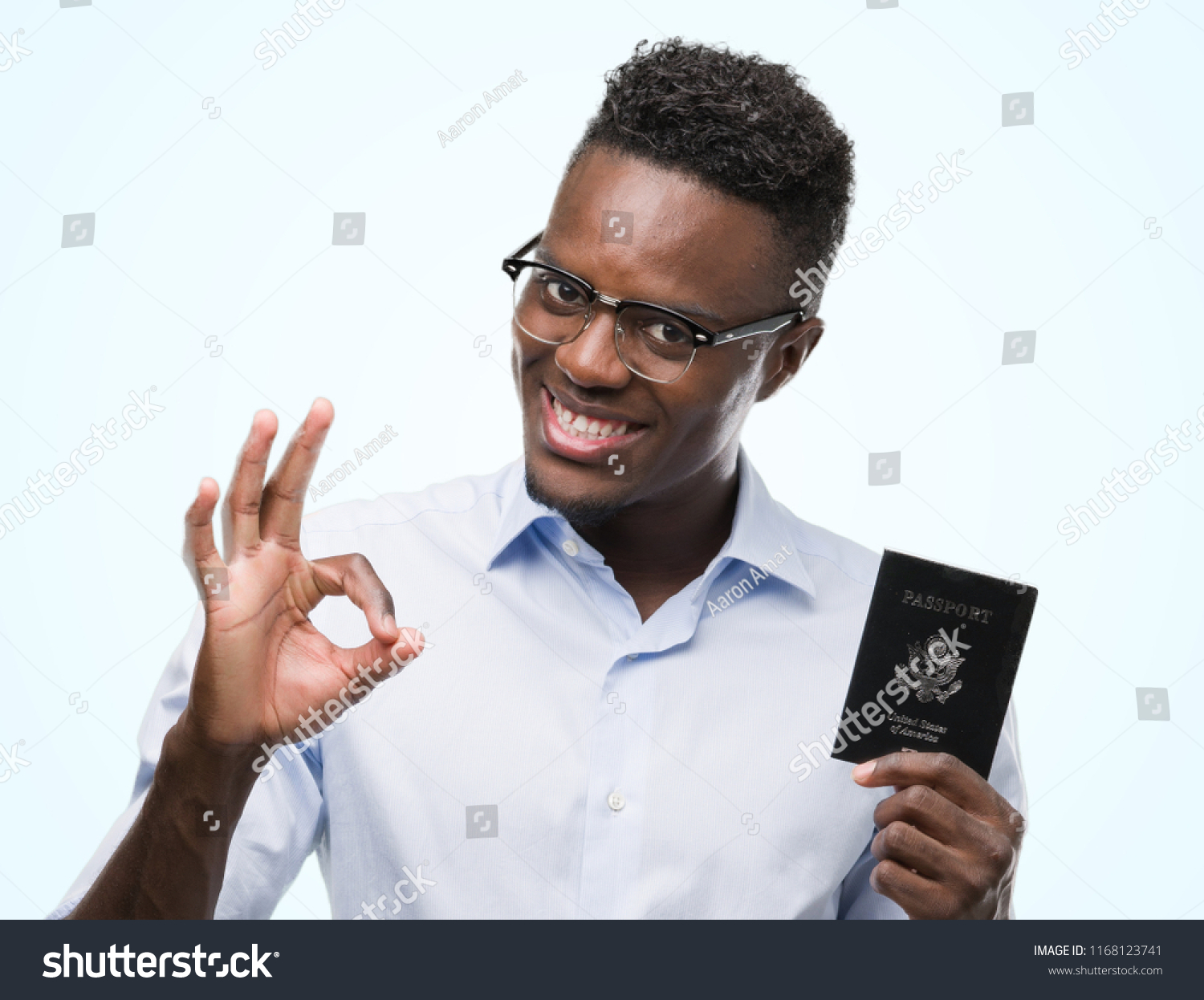 stock-photo-young-african-american-man-holding-passport-of-united-states-of-america-doing-ok-sign-with-fingers-1168123741.jpg