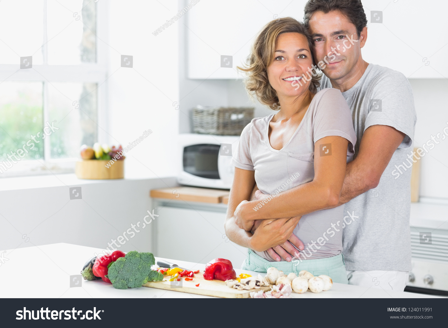Муж обнимает жену на кухне