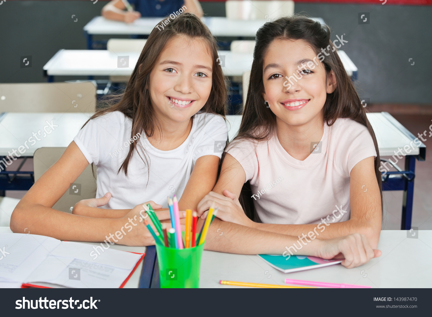 Юные школьницы в классе сидят на столах
