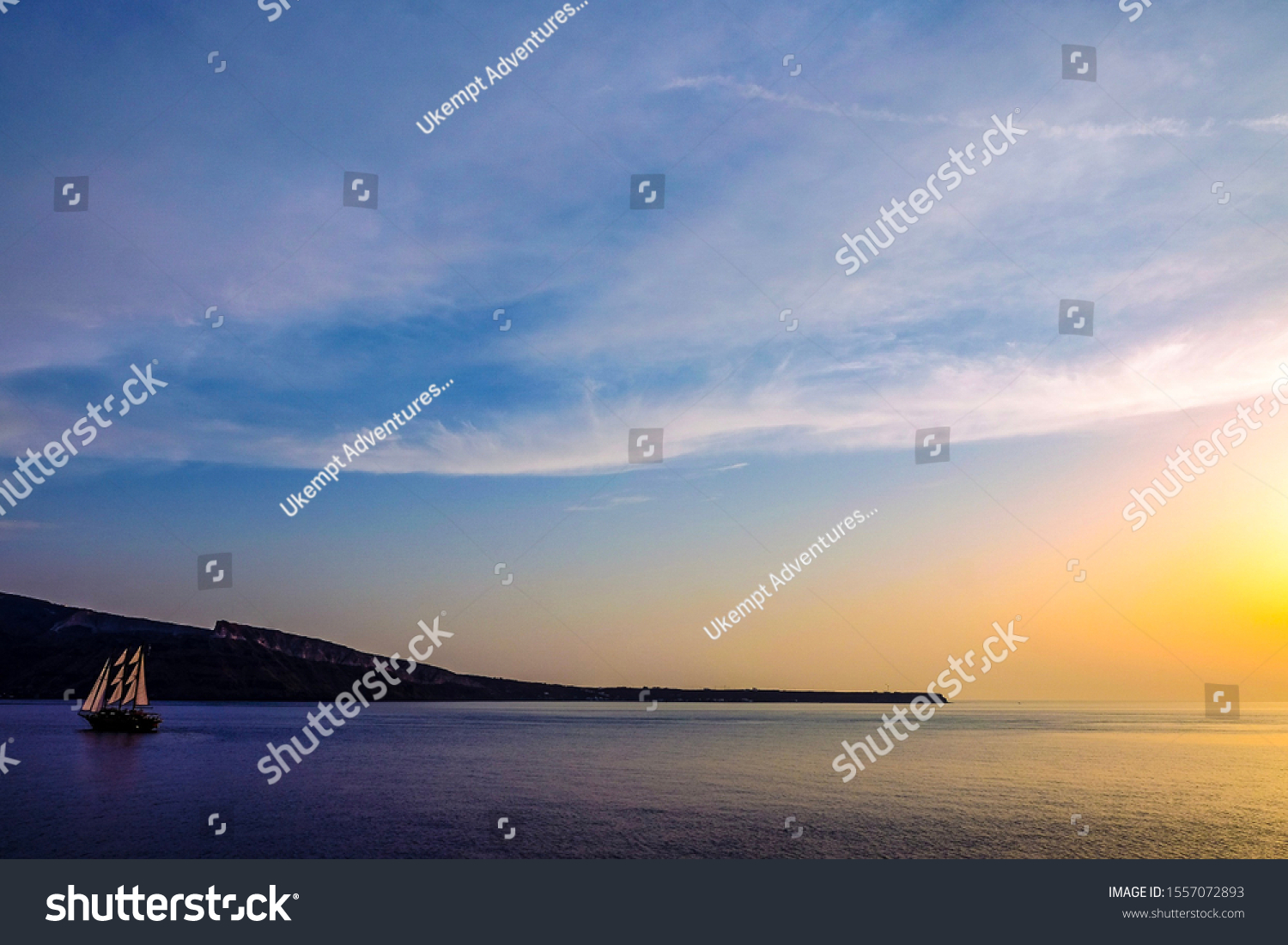 Stock Photo A Sail Boat Rides Off Into The Sunset In Santorini Greece 1557072893 