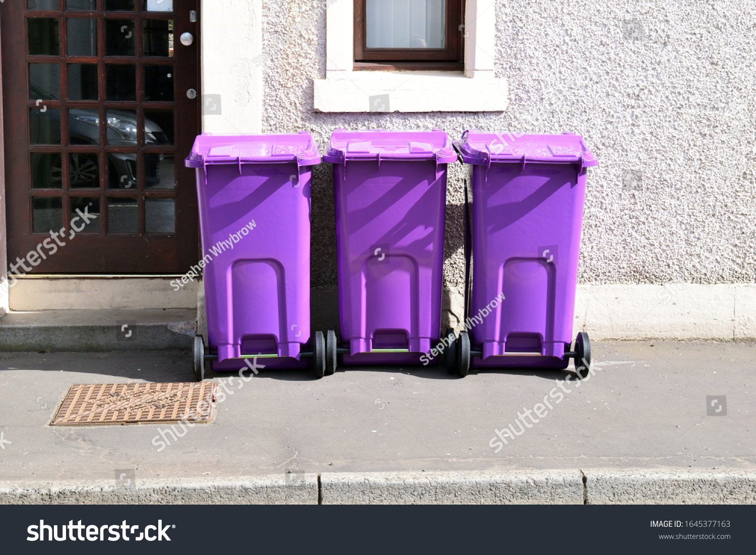 three-purple-plastic-wheeled-waste-bins-stock-photo-1645377163