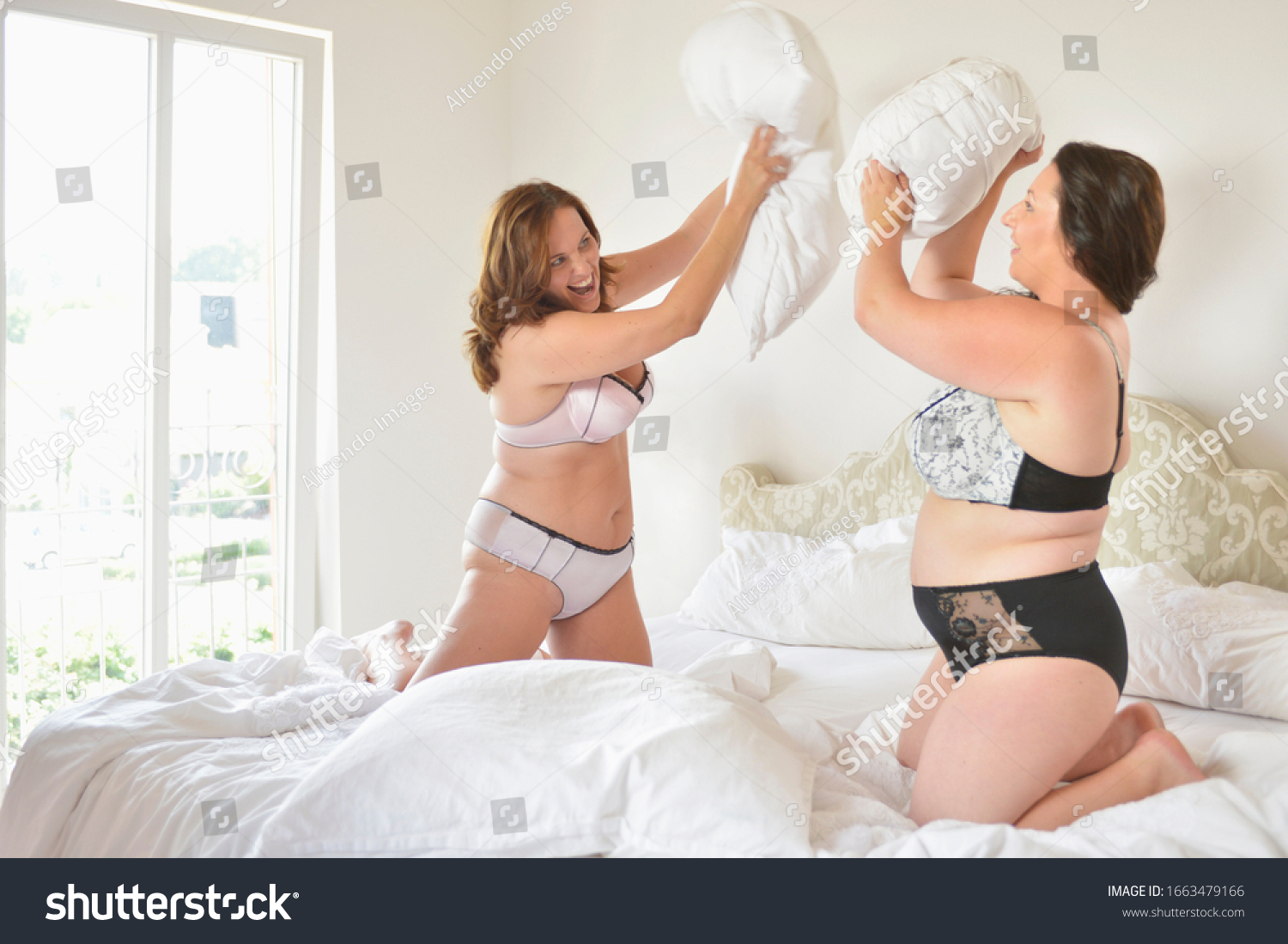 stock-photo-mid-adult-women-in-lingerie-on-bed-having-pillow-fight-1663479166.jpg