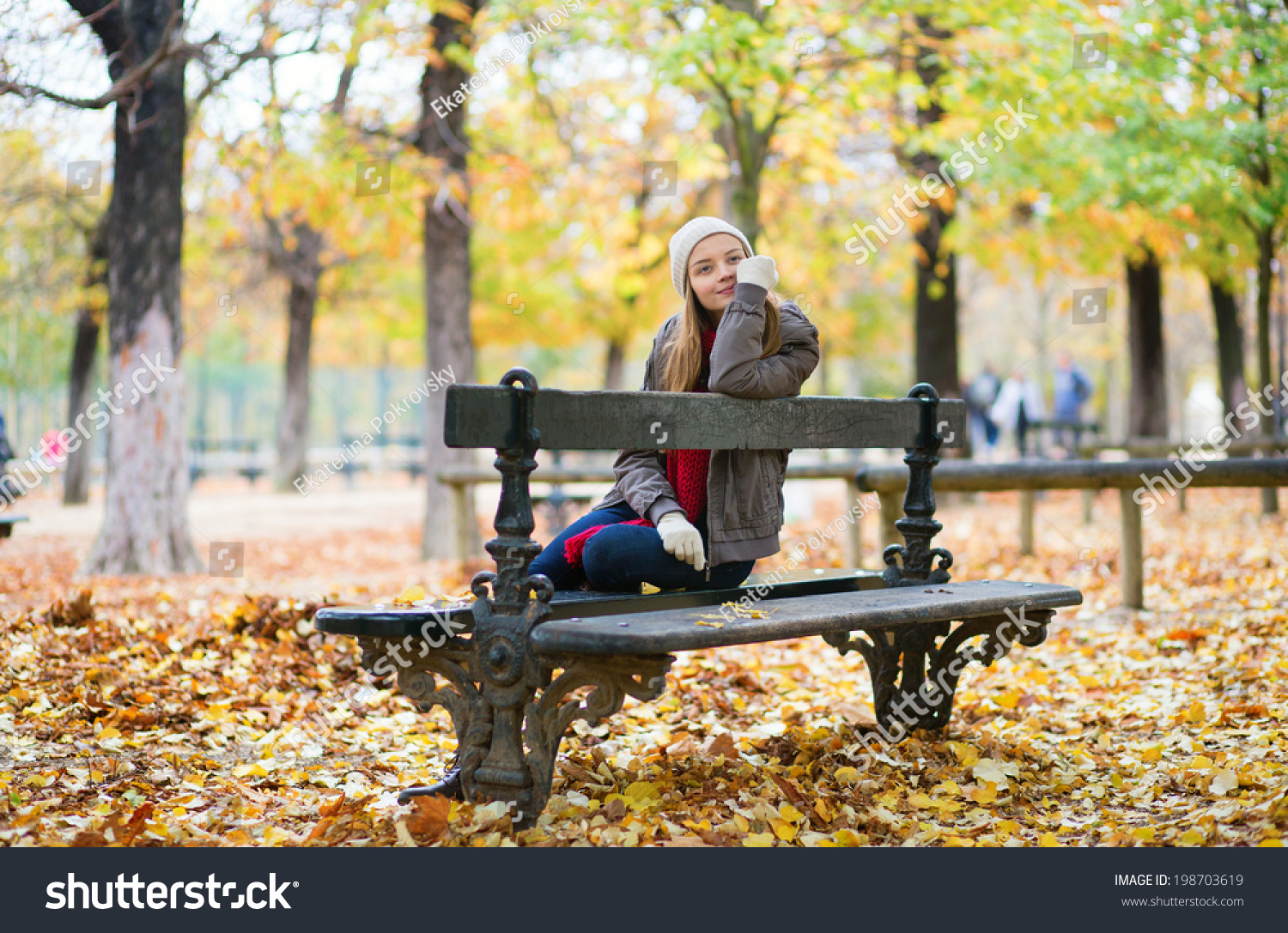 Блондинка сидит на скамейке в осеннем парке
