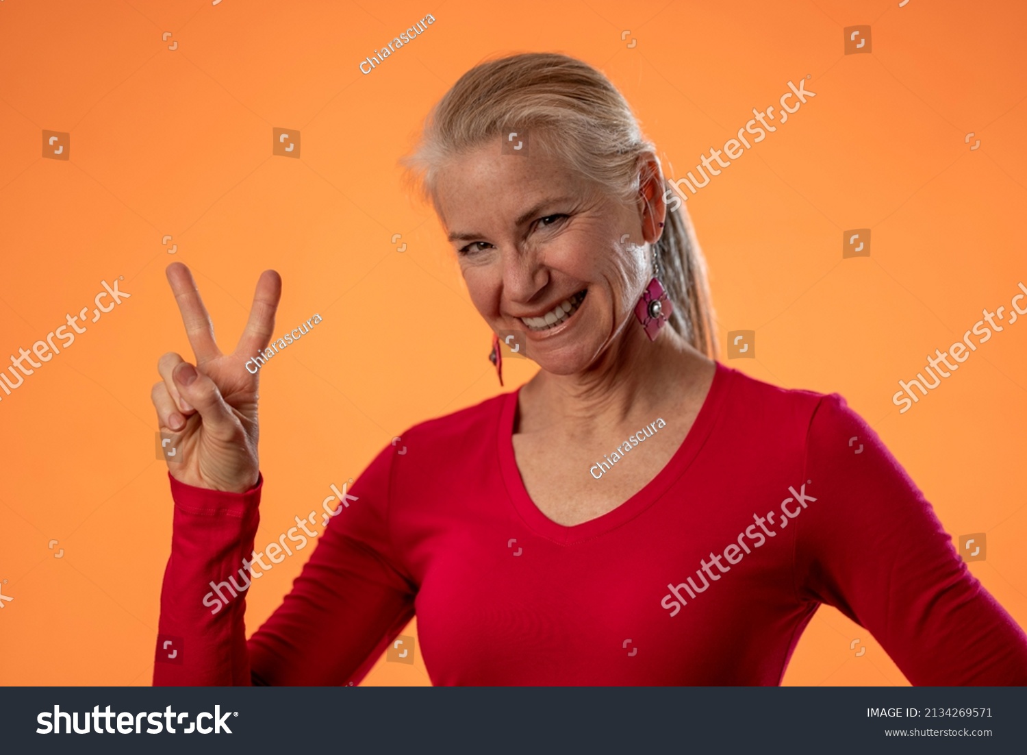 Portrait Mature Woman Giving Peace Sign Stock Photo 2134269571