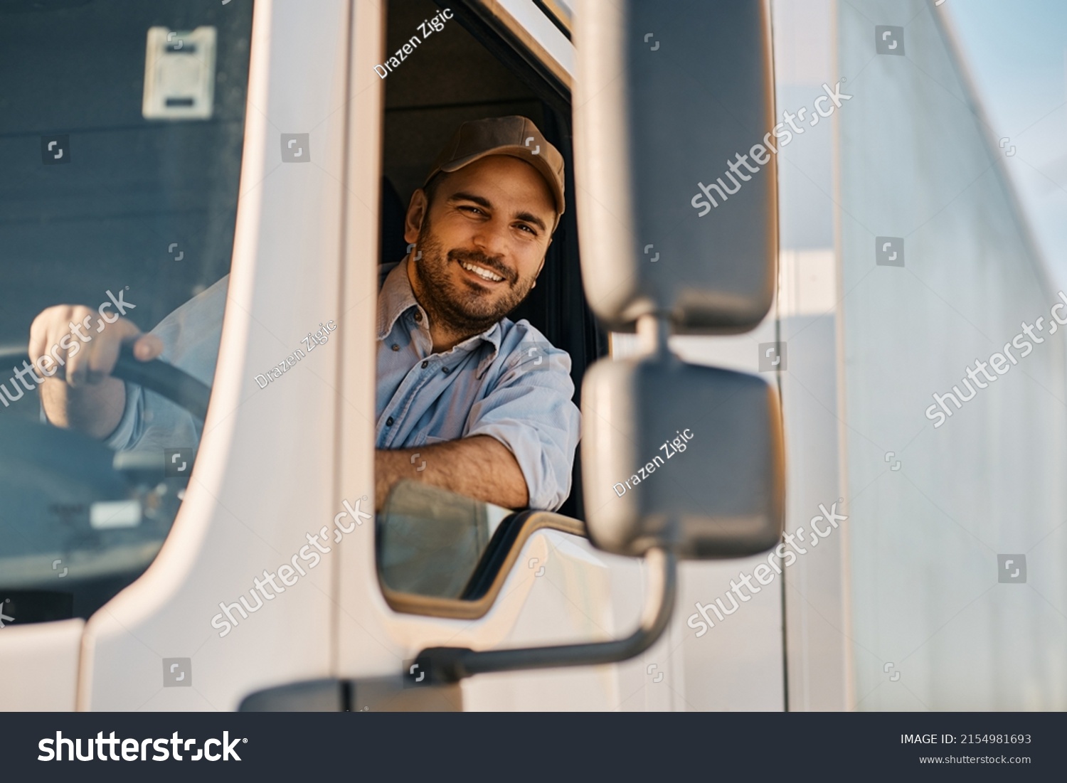 Happy Professional Truck Driver Driving His Foto stock 2154981693 Happy Professional Truck Driver Driving His Foto stock 2154981693