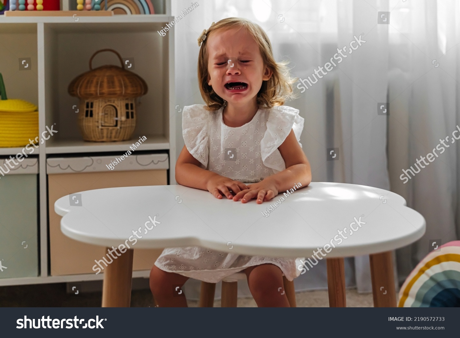 little girl cries at kitchen table saying i didn't