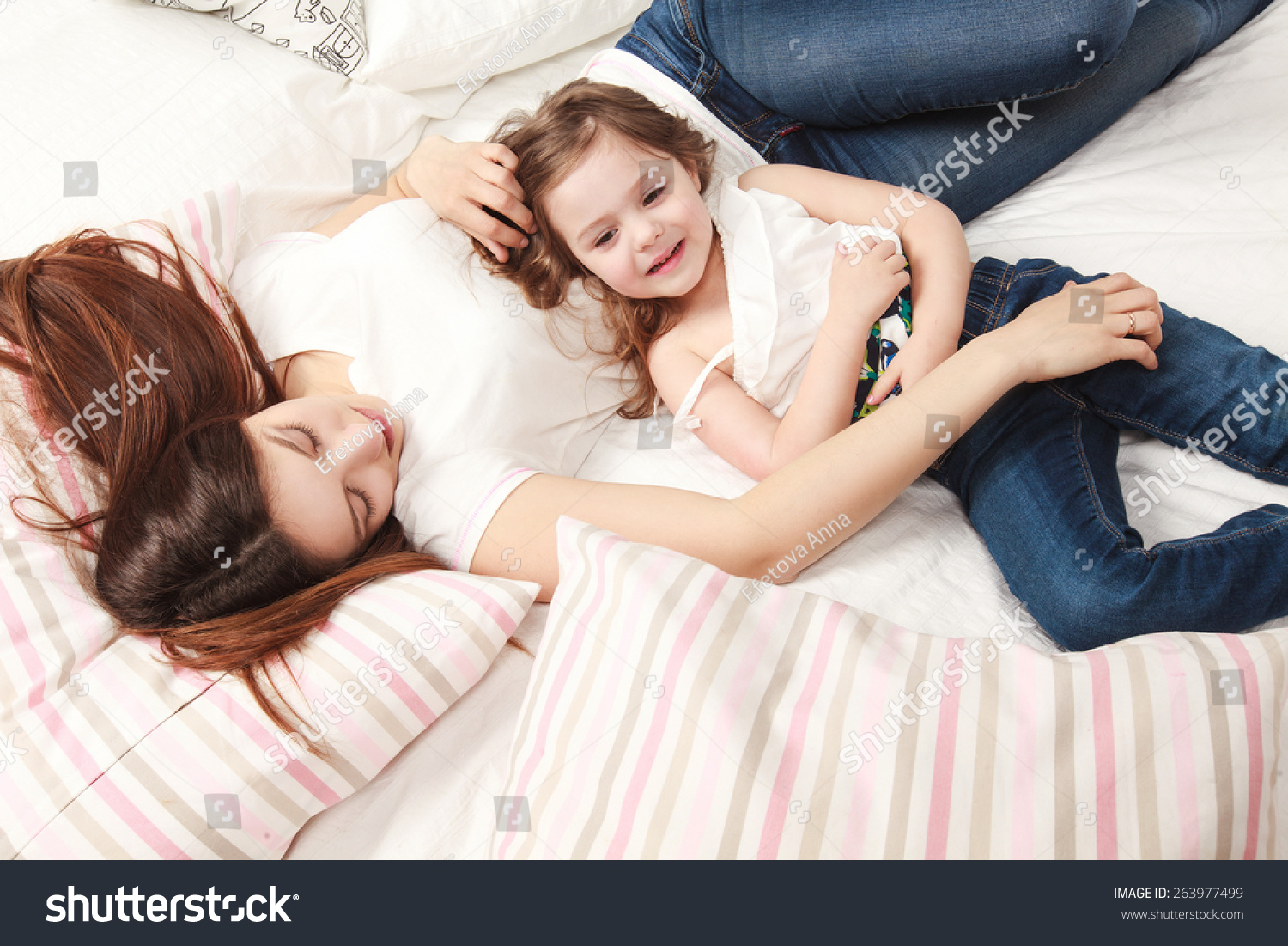 Мама с дочкой лежат на кровати
