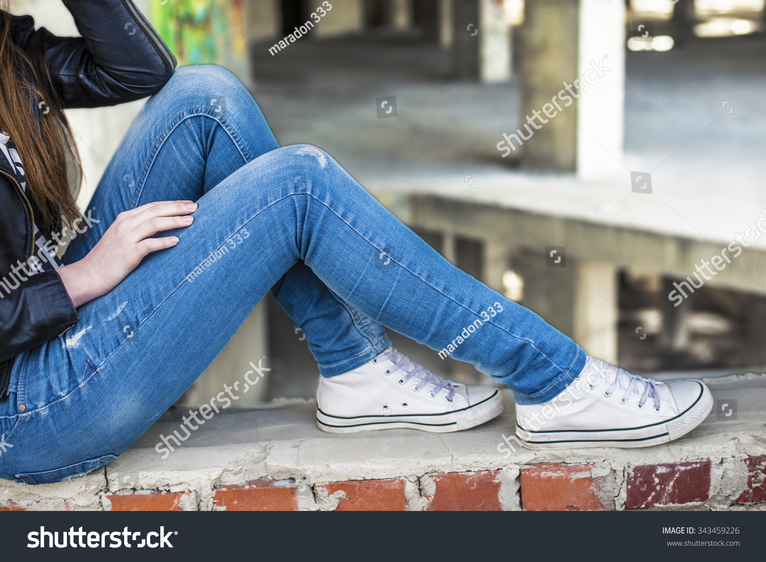 Девушка в джинсах без лица сидит